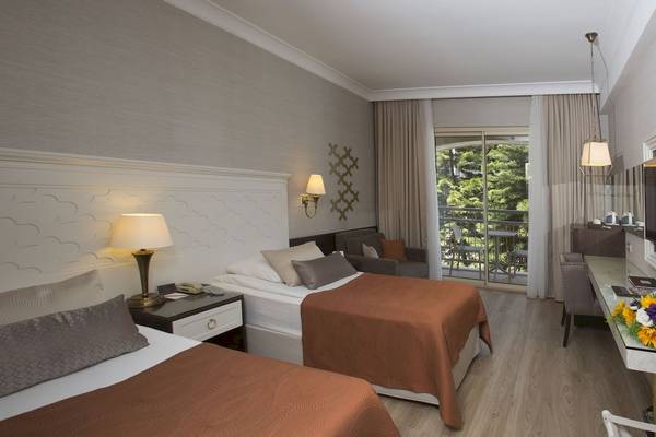 Doppelbettzimmer im Fame Residence Kemer Hotel mit Balkon und Gartenblick.