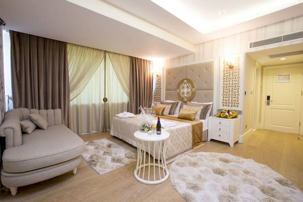 Fame Residence Kemer Suite Schlafzimmer mit großem Bett, Nachttischen, Sofa und Teppichen.