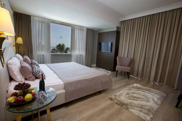 Fame Residence Zimmer mit Bett, Früchteplatte und Meerblick.