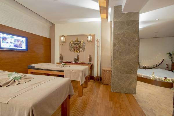 Spa-Behandlungsraum im Fame Residence Hotel mit zwei Behandlungstischen, einer TV-Bildschirmwand und einem Whirlpool.