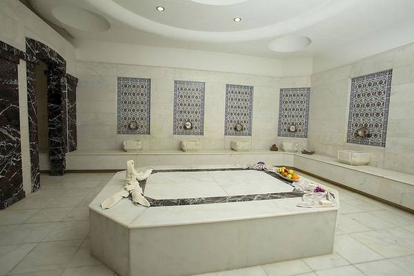 Innenansicht des Dampfbades im Fame Residence Kemer & Spa Hotel mit weißen Marmorfliesen und einem zentralen Becken.
