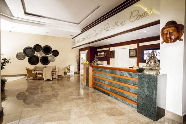 Rezeptionsbereich des Fame Residence Spa & Wellness Center mit Buddha-Statue und Empfangstresen.