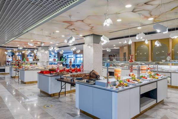 Innenbereich eines Restaurants im Fame Residence Kemer & Spa Hotel mit verschiedenen Essensbuffets und dekorativen Beleuchtungselementen.