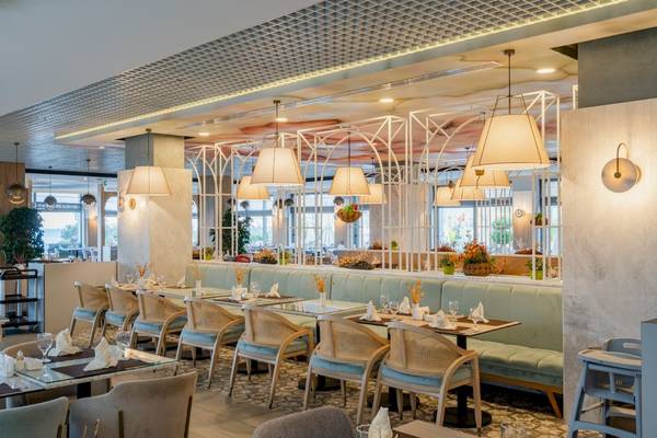 Innenansicht des Restaurants im Fame Residence Hotel & Spa mit Tischen, Stühlen und hängenden Lampen.