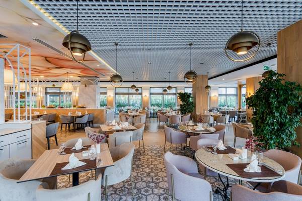 Innenansicht des Restaurants im Fame Residence Kemer & Spa mit gepolsterten Stühlen und Tischen.