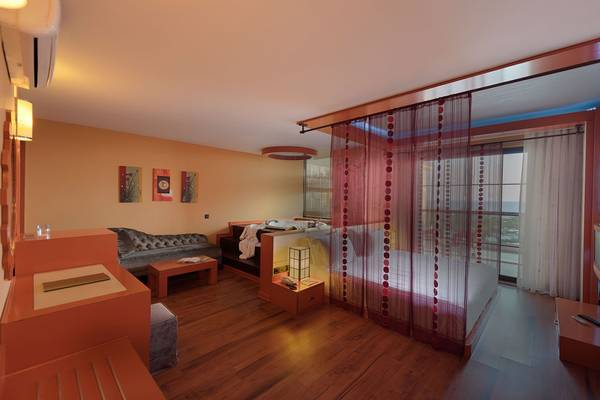 Innenansicht eines Zimmers im Siam Elegance Hotels & Spa mit Bett, Sofa, Tisch und Klimaanlage.