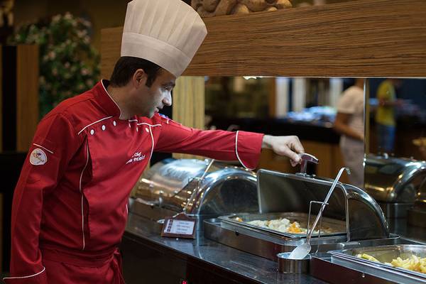 Koch im Siam Elegance Hotels & Spa serviert Essen in einer großen Schale
