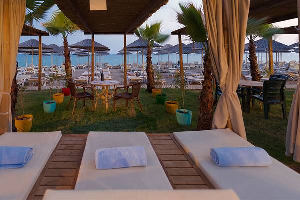Strandszene des Siam Elegance Hotels & Spa mit Sonnenliegen, Tischen und Sonnenschirmen.