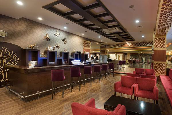 Empfangsbereich des Siam Elegance Hotels & Spa mit Bar, roten Stühlen und Sofas.