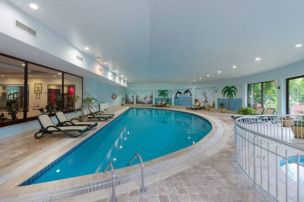 Innenpool im Siam Elegance Hotels & Spa mit Loungeliegen und tropischen Wandmalereien.