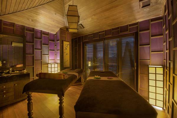 Innenansicht des Massageraums im Siam Elegance Hotels & Spa mit zwei Massagetischen, dekorativen Lampen und Holzelementen.