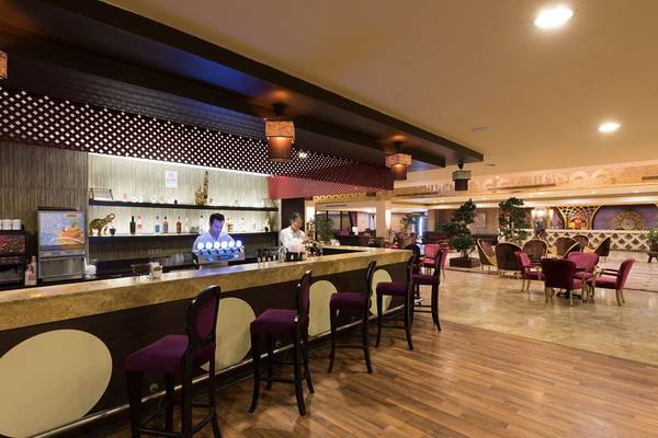 Innenansicht der Bar im Siam Elegance Hotel mit Barkeeper und Gästen an Tischen.