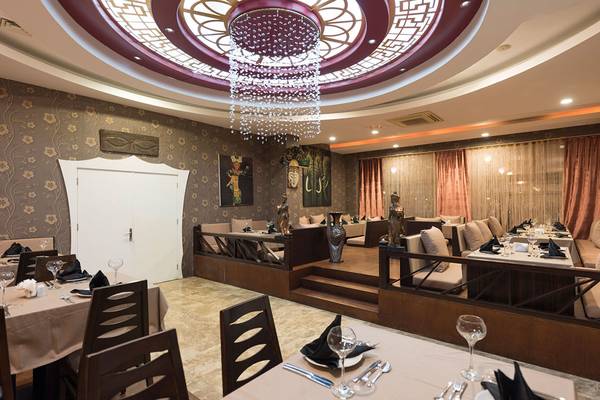 Innenansicht des Restaurants im Siam Elegance Hotels & Spa, mit eleganten Tischeinstellungen und einer beeindruckenden Deckenleuchte.