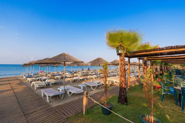 Strandszene im Siam Elegance Hotels & Spa mit vielen Sonnenliegen und Sonnenschirmen.