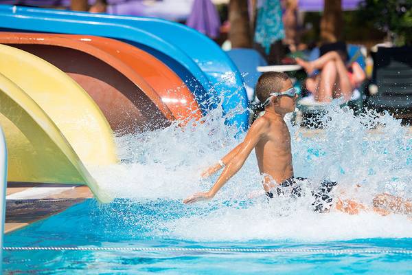 Ein Junge schwimmt im Wasser einer Poolrutsche im Siam Elegance Hotels & Spa.