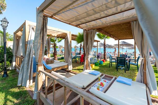 Loungebereich am Strand des Siam Elegance Hotels & Spa mit Sonnenschirmen und Liegen.