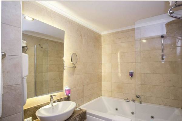 Ein Badezimmer im Side Alegria Hotel & Spa mit einer Badewanne, einem Waschbecken und einem Spiegel.