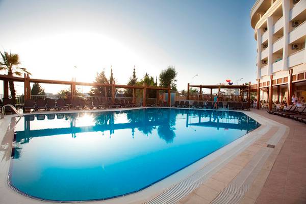 Außenpool des Side Alegria Hotel & Spa bei Sonnenuntergang mit Lounge-Stühlen