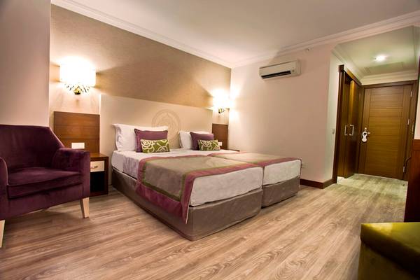 Doppelbett-Zimmer im Side Alegria Hotel & Spa mit violettem Stuhl und hölzernem Boden.