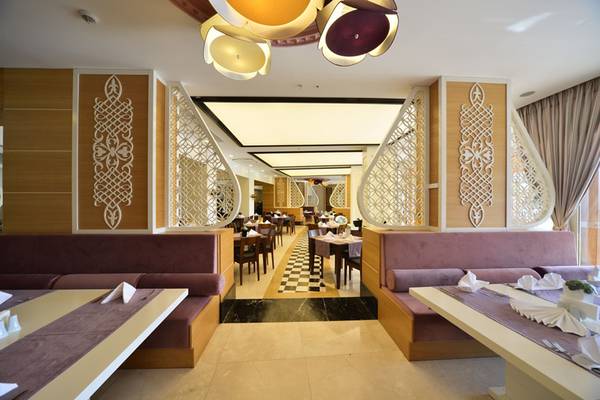 Innenansicht des Restaurants im Side Alegria Hotel & Spa mit braunen Sitzbänken und Marmorboden.