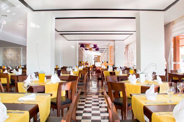 Innenansicht des Restaurants im Side Alegria Hotel & Spa mit gelben Tischdecken und braunen Stühlen.