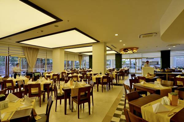 Innenansicht des Restaurants im Side Alegria Hotel & Spa mit gedeckten Tischen und gelben Tischdecken.