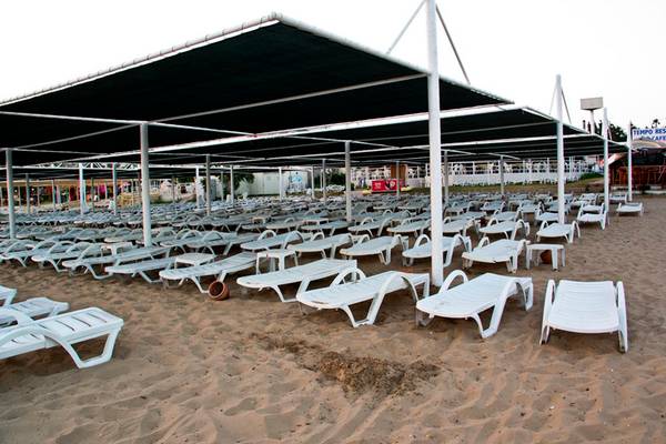 Strand mit vielen Sonnenliegen unter Markisen auf goldenem Sand