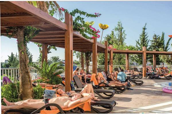 Gäste entspannen auf Sonnenliegen im Schatten am Poolbereich des Side Alegria Hotel & Spa.
