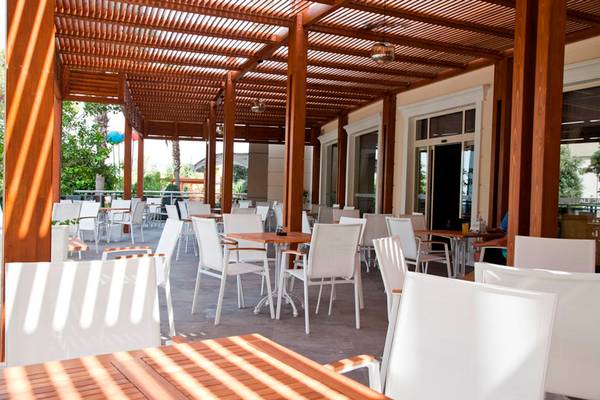Terrasse des Side Alegria Hotel & Spa mit weißen Tischen und Stühlen unter einem Holzpergola.