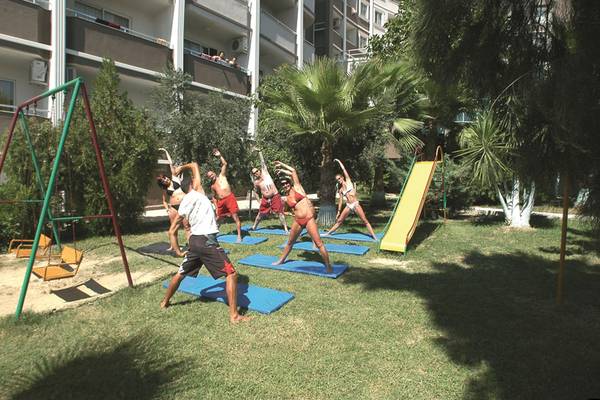 Eine Gruppe von Menschen praktiziert Yoga im Garten des Side Alegria Hotel & Spa.