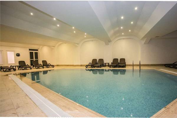Innenpool im Side Alegria Hotel & Spa mit Liegestühlen und beleuchteter Decke.