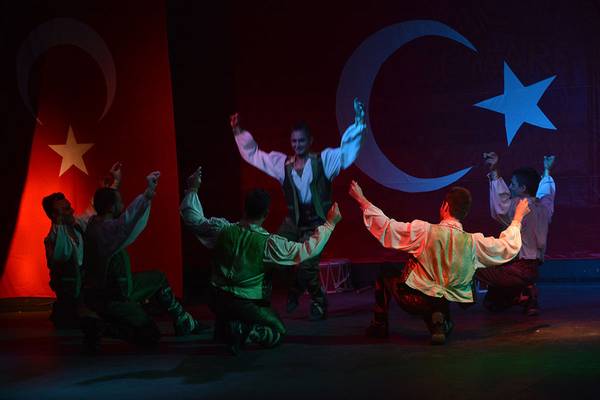 Fünf Tänzer auf der Bühne vor einer türkischen Flagge.