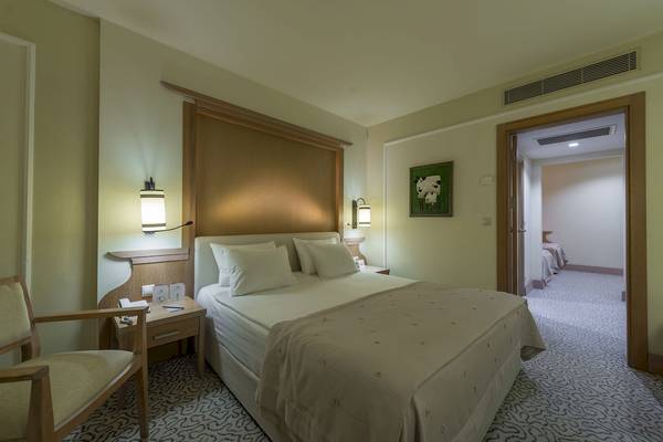 Ein Doppelbettzimmer im Dobedan Beach Resort Comfort Hotel mit beigen Wänden und einem gemusterten Teppich.