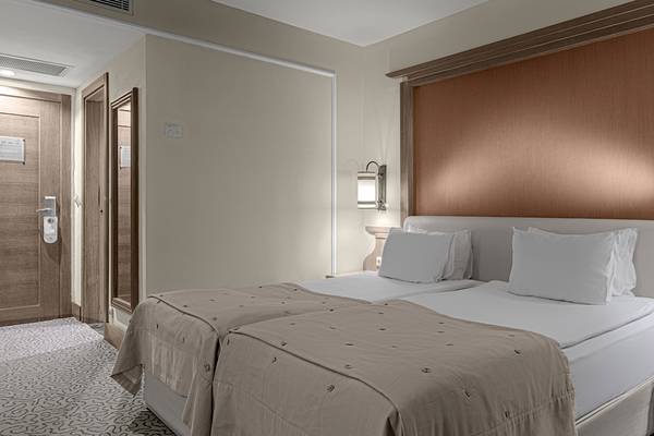 Schlafzimmer im Dobedan Beach Resort Comfort mit zwei Betten, Kissen, Decken und einer Wandlampe.