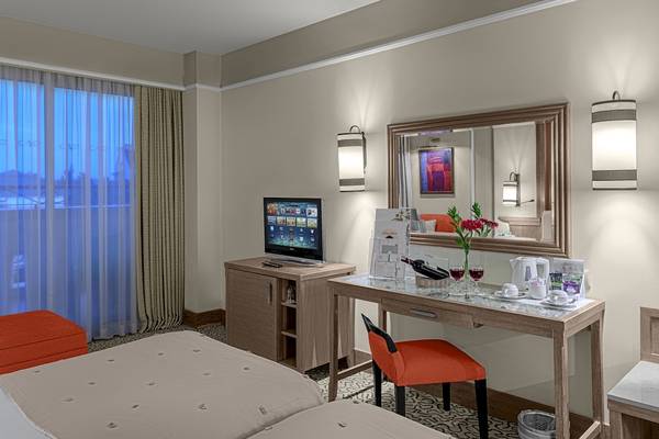 Hotelzimmer im Dobedan Beach Resort Comfort mit Fernseher, Schreibtisch und Fenster mit Vorhängen.