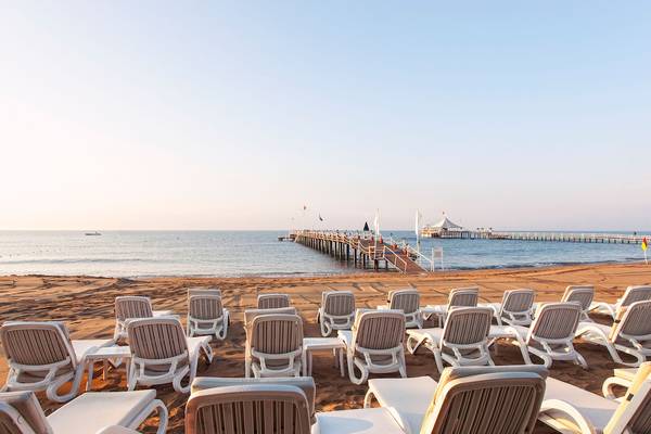 Dobedan Beach Resort Comfort: Strand mit Lounge-Stuhlreihen und einer Pier im Hintergrund.