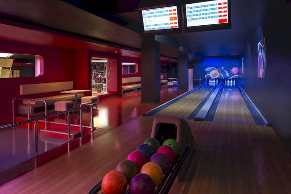 Bowlingbahn im Dobedan Beach Resort Comfort mit roten Wänden und Bowlingkugeln.
