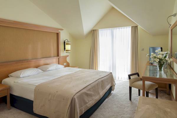 Hotelzimmer im Dobedan Beach Resort Comfort mit Bett, Tisch, Stuhl und Fernseher.