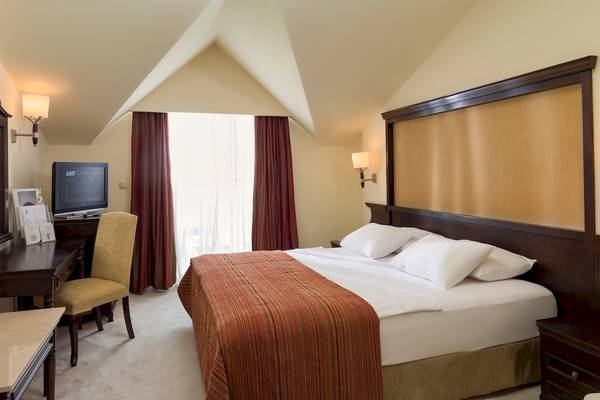 Ein Hotelzimmer im Dobedan Beach Resort Comfort mit einem Bett, Schreibtisch, Stuhl und Fernseher.