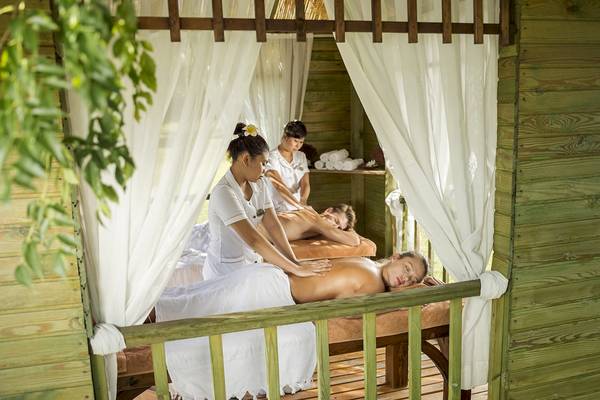 Massagebehandlung im Dobedan Beach Resort Comfort mit zwei Frauen, die Männer massieren, die auf einem Bett liegen.