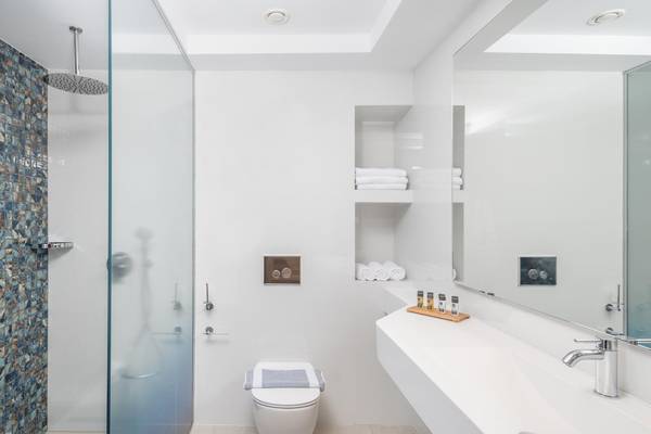 Badezimmer im Lyttos Mare Hotel mit Glasdusche, Toilette und Waschbecken.