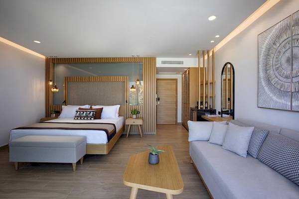 Innenansicht des Schlafzimmers im Lyttos Mare Hotel mit Doppelbett, Sofa, Tisch und Dekor.