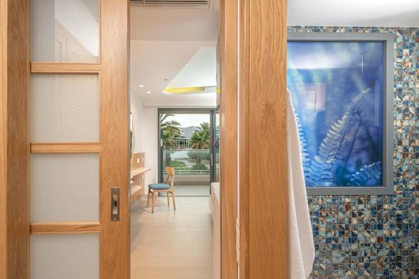 Innenansicht eines Zimmers im Hotel Lyttos Mare mit offenem Holztür, Holzmöbel und Ausblick auf Garten