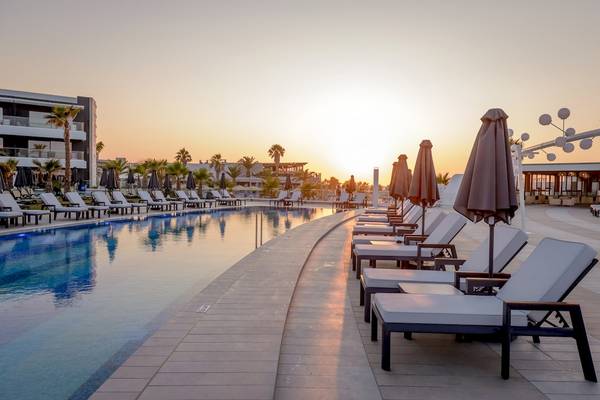 Sonnenuntergang am Poolbereich des Lyttos Mare Hotels mit Liegen und Sonnenschirmen.