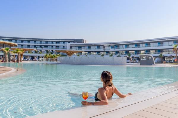 Eine Frau genießt ein Getränk im Pool vor dem Lyttos Mare Hotel.