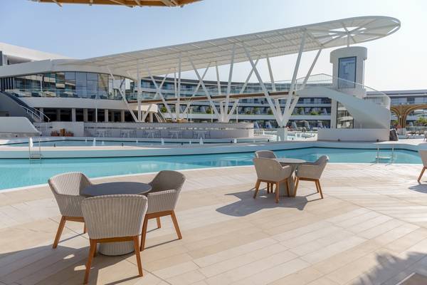 Poolbereich des Lyttos Mare Hotels mit Tischen und Stühlen im Freien.