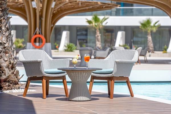 Zwei weiße Sessel mit blauen Kissen stehen neben einem runden Tisch am Pool des Lyttos Mare Hotels.