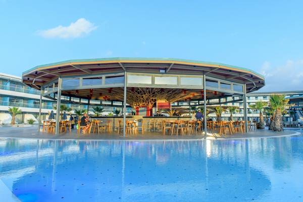 Lyttos Mare Hotel Pool Bar mit Gästen und Sonnenschirmen bei blauem Himmel