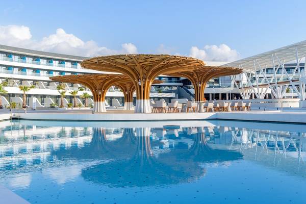 Pool-Terrasse im Lyttos Mare Hotel mit modernen Holzpavillons und Lounge-Stuhlreihen.
