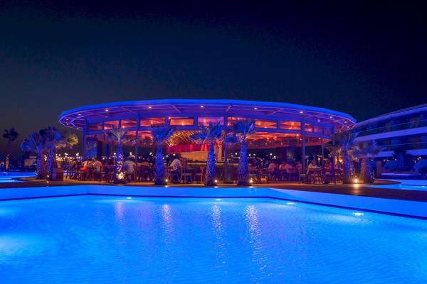 Nachtliche Poolbar im Lyttos Mare Hotel mit blauer Beleuchtung und Palmen